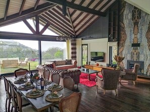 Ein geräumiger Wohnbereich mit Esstisch, gedecktem Tisch für eine Mahlzeit, einer Couch und einem Kamin.