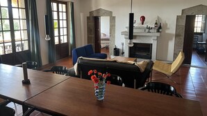A spacious living area with a fireplace, a dining table, and a sofa. - At the foot of the Pyrenees (Maçanet de Cabrenys)