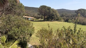 A rural landscape with a house, a grassy field, and trees. - At the foot of the Pyrenees (Maçanet de Cabrenys)