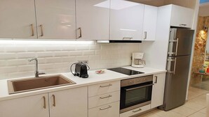 Eine moderne Küche mit weißen Schränken, einem Edelstahlkühlschrank, einer Kaffeemaschine und einem Backofen.