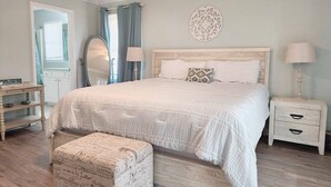 A bedroom with a large bed, bedside tables, a mirror, and a decorative wall piece. - 600 Steps, Great Family Beach House, Pet friendly & Close to Beach (Pawleys Island)