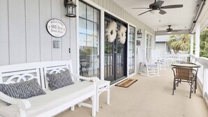 A porch with a white bench, a table, and chairs. - 600 Steps, Great Family Beach House, Pet friendly & Close to Beach (Pawleys Island)