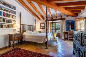 A four-poster bed with a wooden headboard, a bookshelf filled with books, a desk with a chair, and a large window with curtains. - Spacious 9-bedroom private villa with AC in lovely Sóller (Sóller)