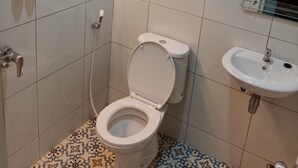 A bathroom with a toilet, shower, and sink.