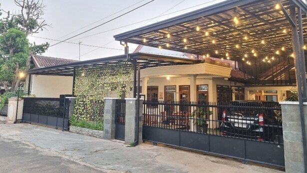 A covered outdoor area with a metal roof, a black fence, and a car parked inside.