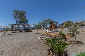 A beach area with hammocks, wooden structures, and potted plants. - Family Beachfront Apartment with Sea View in Agia Galini, Crete (Agia Galini)