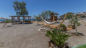 Una zona junto a la playa con hamacas, estructuras de madera y plantas en macetas.