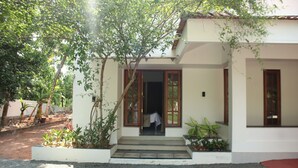 A white building with a covered entrance, steps leading up to it, and a gravel driveway. - Vayal Varam Private Villa Peaceful Nature Stay Kollam (Kollam)