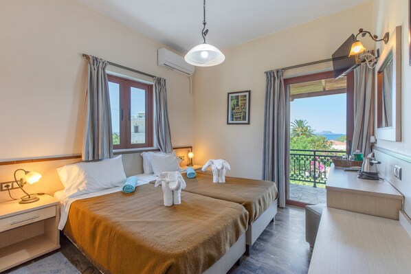 Ein Hotelzimmer mit zwei Betten, einem Balkon, einer Küchenzeile und Meerblick.