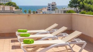 A rooftop terrace with lounge chairs and a view of the sea. - Apartment Son Baulo Pera (Ca´n Picafort)
