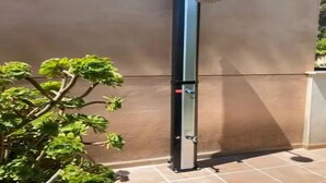 A vertical structure with a metallic finish, possibly a water feature or a piece of outdoor equipment, next to a wall with a plant. - Apartment Son Baulo Pera (Ca´n Picafort)