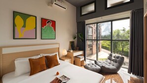 Una habitación de hotel moderna con una cama grande, un escritorio, una silla y un balcón con vistas.
