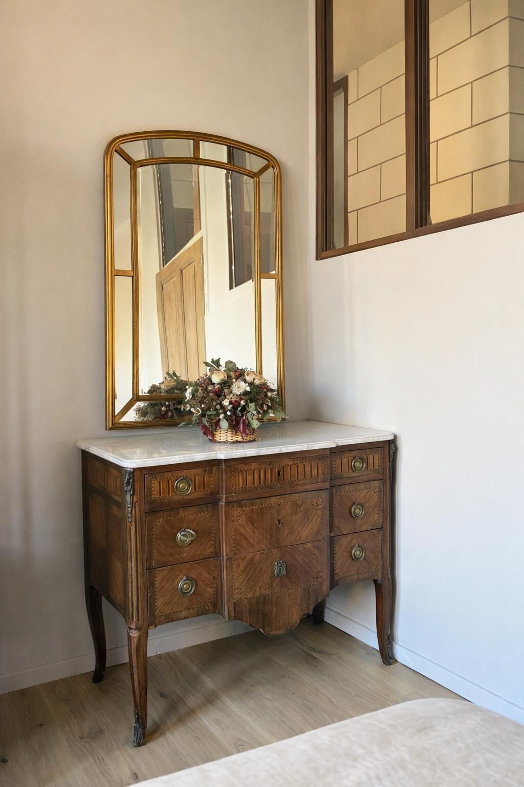 Un mobile bagno in legno con uno specchio e un vaso di fiori.