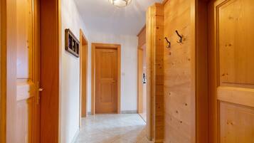 Un corridoio con porte in legno, un lampadario e un pavimento piastrellato.