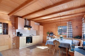 Un intérieur en bois comprenant une cuisine, un coin repas et une fenêtre avec des rideaux.