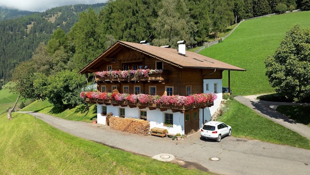 A traditional chalet with a sloped roof, wooden balconies with flower boxes, and a view of a green valley. - Farmhouse "Ferienwohnung Pendlhof" with Mountain Views, Shared Garden, and Wi-Fi (Sankt Pankraz)
