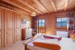 Une chambre dans une cabane en bois, avec un lit, une commode et une fenêtre donnant sur les montagnes.