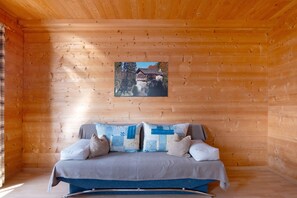 Un interior de madera con una cama, almohadas y un cuadro en la pared.