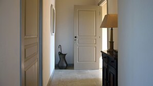 Un pasillo con una puerta cerrada, un florero y una lámpara.