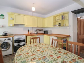 Una cocina compacta con gabinetes amarillos, lavadora, estufa y microondas.