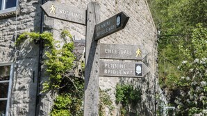 Segnaletica in legno con frecce direzionali che indicano Woo Dale, Chee Dale e Pennine Bridleway.
