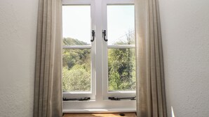 Una stanza con finestra, tende e vista sul verde.
