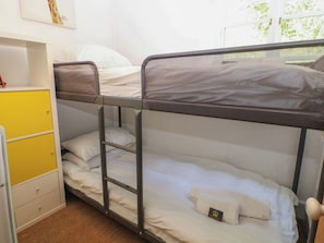 Una cama litera con escalera, un armario amarillo y un estante con una fotografía.