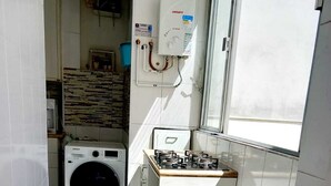 Una cucina compatta con fornello a gas, lavatrice e scaldabagno.
