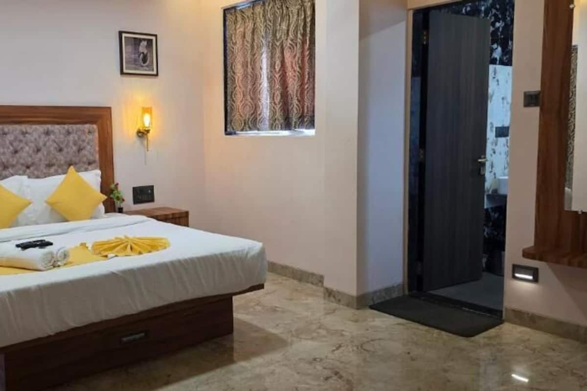 Een hotelkamer met een groot bed, nachtlampjes, een deur en een klein tafeltje.
