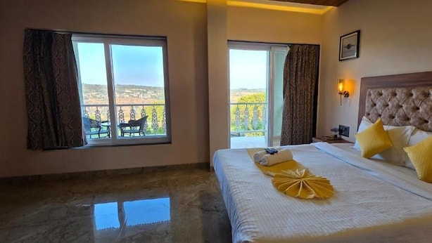 Ein Hotelzimmer mit einem Bett, zwei Fenstern, einem Balkon und Blick auf die Landschaft.