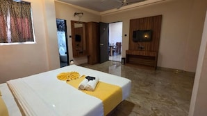 Ein Hotelzimmer mit Bett, Fernseher und einem durch eine offene Tür einsehbaren Badezimmer.