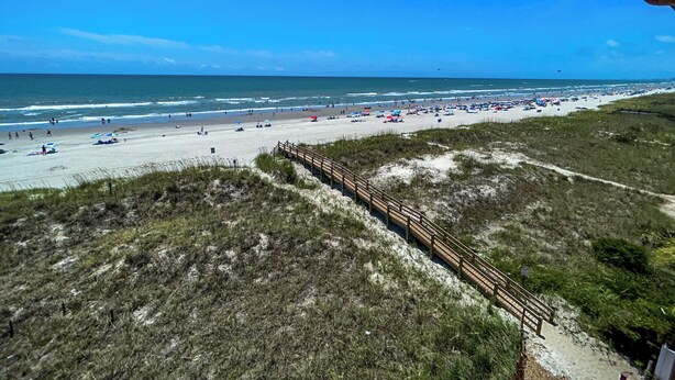 A beach with a wooden boardwalk leading to the shore, sandy beach, and ocean. - 10% off 3-7 nights through Dec. 1BR 1BA OF condo. Outdoor pool. Cozy getaway. (North Myrtle Beach)