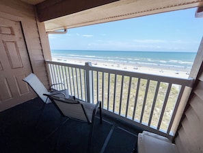Ein Balkon mit Blick auf den Strand, eine Tür und zwei Stühle.