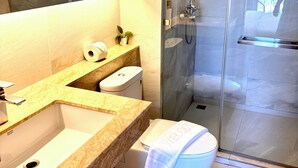 A modern bathroom with a marble sink, toilet, and glass-enclosed shower. - Coconut Studio Aonang (Krabi)