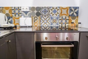 Eine Küche mit Edelstahlbackofen, Mikrowelle und gefliestem Küchenrückwand.