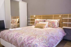 Um quarto com cama, guarda-roupa e mesa de cabeceira.