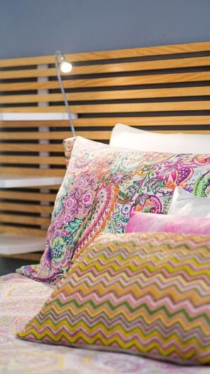 Ein Bett mit farbenfrohen, gemusterten Kissen und einem hölzernen Kopfteil.