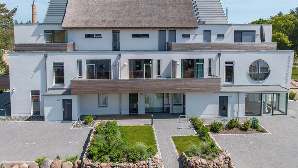 A modern two-story building with a flat roof, large windows, and a circular glass door. - 2-room apartment in Karlshagen on Usedom with terrace, close to the beach (Karlshagen)