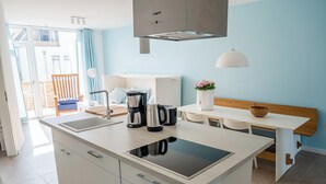 A modern kitchen with a central island, a dining table, and a bench. - 2-room apartment in Karlshagen on Usedom with terrace, close to the beach (Karlshagen)