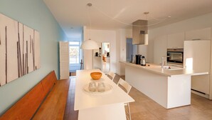 A modern kitchen with a central island, white cabinetry, and a dining area with a bench and table. - 2-room apartment in Karlshagen on Usedom with terrace, close to the beach (Karlshagen)