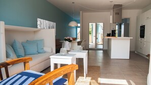 A modern living room with a sofa, a dining table, and a kitchen area with cabinets and appliances. - 2-room apartment in Karlshagen on Usedom with terrace, close to the beach (Karlshagen)