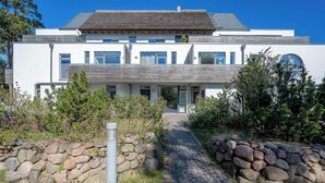 Ein modernes, zweistöckiges Haus mit einem Kiesweg, der zum Eingang führt.
