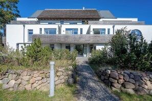 A modern two-story house with a stone pathway leading to the entrance. - Bright apartment in Karlshagen on Usedom with covered terrace, close to the beach (Karlshagen)