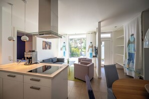 A modern kitchen with a central island, a dining area with a table and chairs, and a living space with a sofa and a chair. - Bright apartment in Karlshagen on Usedom with covered terrace, close to the beach (Karlshagen)