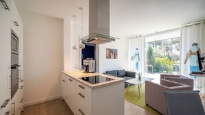 Eine moderne Küche mit Kochinsel, integrierten Geräten und einer Essecke mit Sofa und Tisch.