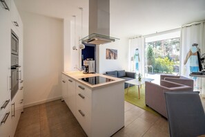 A modern kitchen with a central island, built-in appliances, and a dining area with a sofa and table. - Bright apartment in Karlshagen on Usedom with covered terrace, close to the beach (Karlshagen)