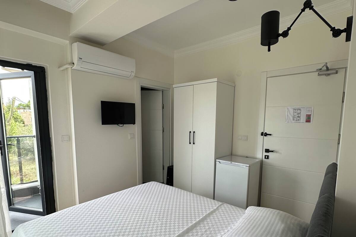 A bedroom with a bed, a wardrobe, a television, and a door with a notice.