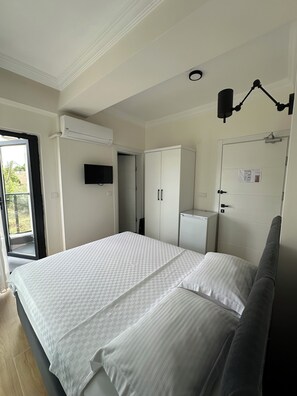 Un dormitorio con cama, armario, televisor y puerta con un aviso.