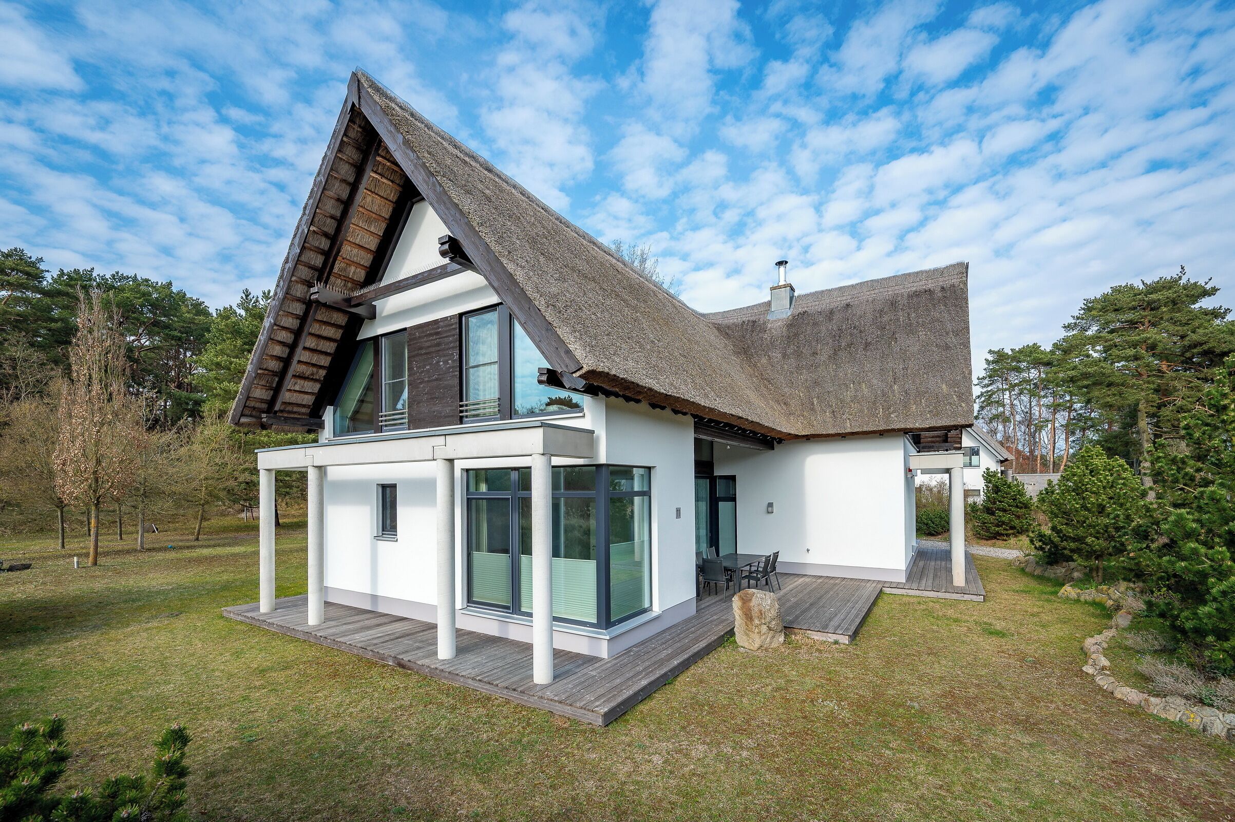 A modern house with a sloped roof, large windows, and a wooden deck.
