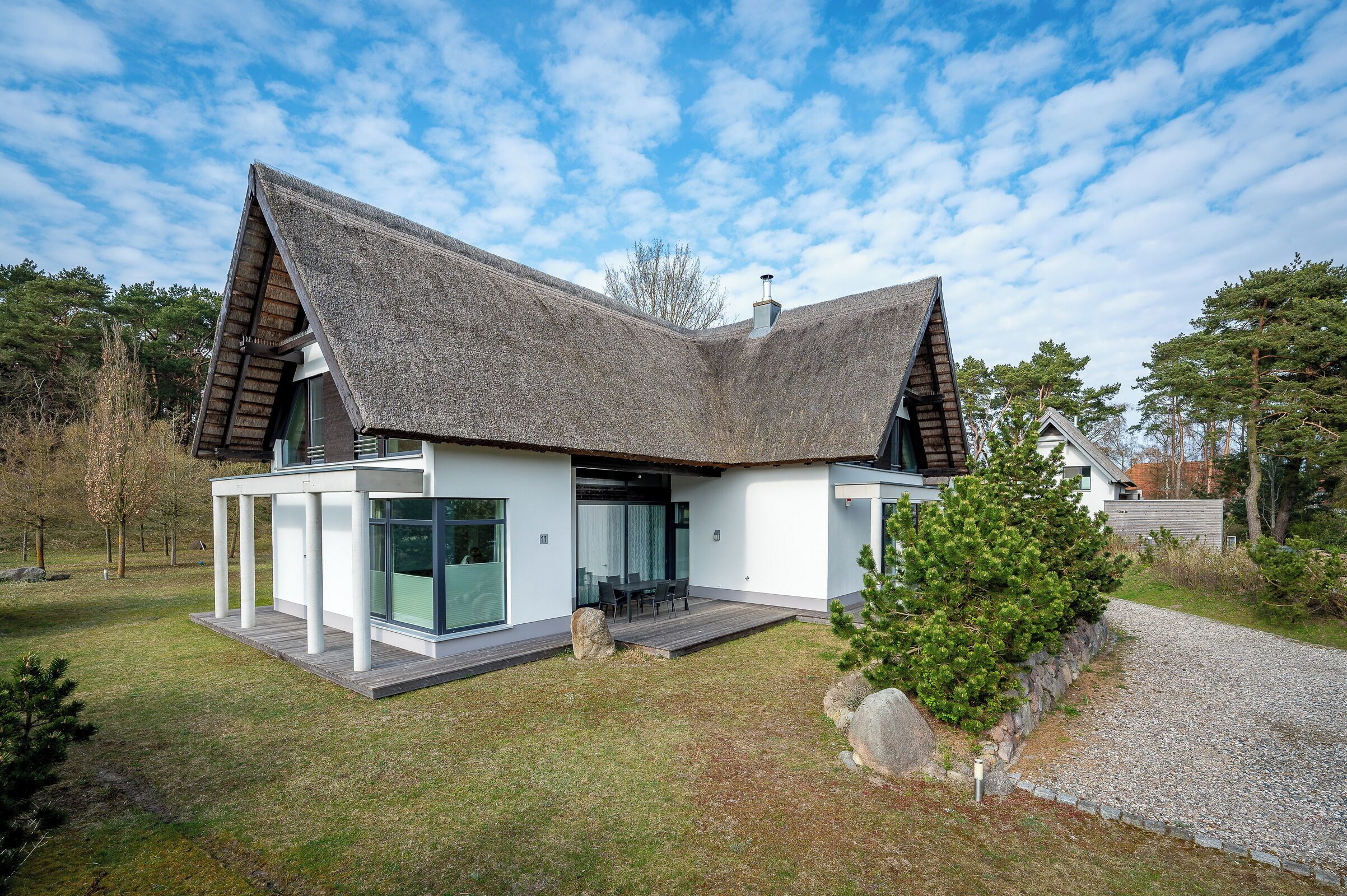 Ein modernes Haus mit Satteldach, großen Fenstern und einem gepflegten Rasen.